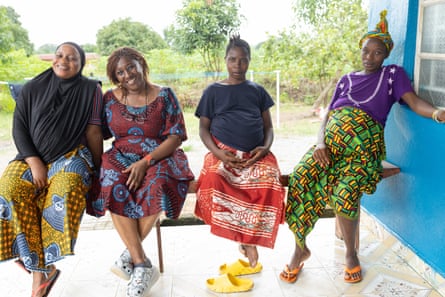 A women in an African-print dress sits with three pregnant women on a bench