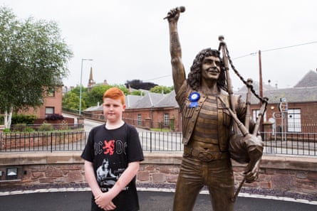A fan next to the life-size bronze statue of AC/DC’s Bon Scott in Kirriemuir.