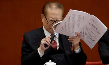 Former Chinese President Jiang Zemin uses a magnifying glass to read Chinese President Xi Jinping’s report during the opening of the 19th National Congress of the Communist Party of China.