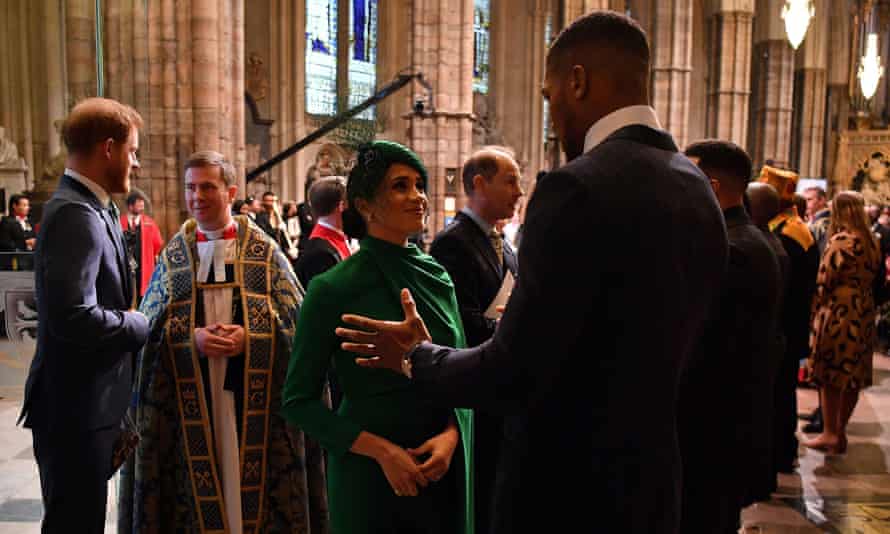 The Duchess of Sussex speaks with the British boxer Anthony Joshua as she leaves the service.
