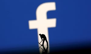A figurine in front of the Facebook logo
