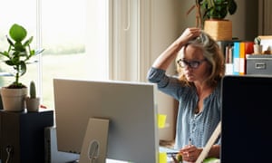 Stressed woman with hand in hair holding credit card at computer in home office
