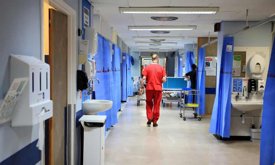 A member of staff walks down a UK hospital ward