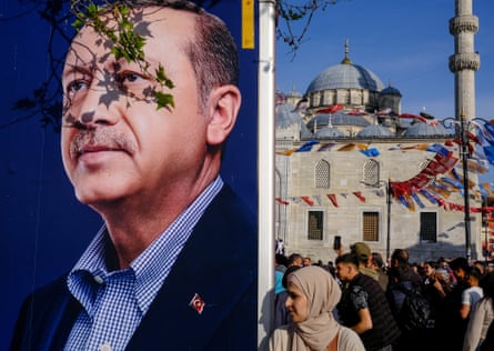 A woman in a headscarf walks past a vehicle with a billboard of Recep Tayyip Erdoğan