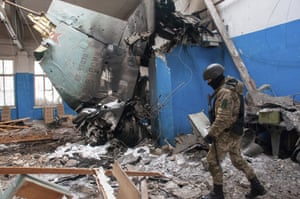 A soldier walks past the vertical tail fin of a Russian Su-34 bomber in a damaged building