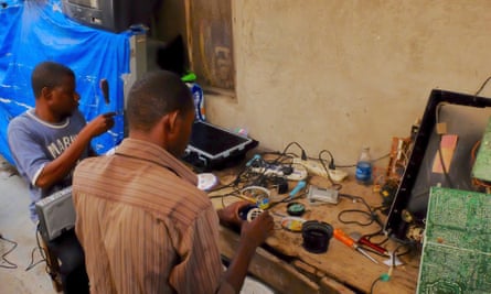 Two men, working in Zanzibar market, repair imported TVs from Europe