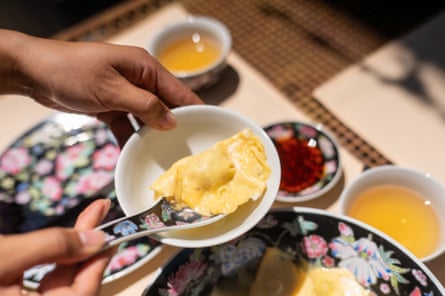 An egg-wrapped omelette being scooped into a bowl.