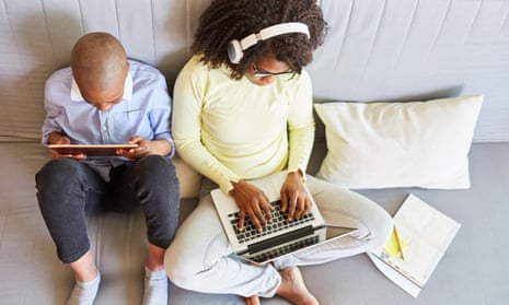Black mother and son watching screens on sofa