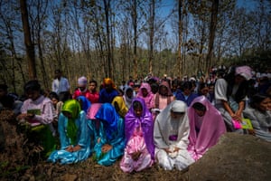 Women in colourful saris kneel in prayer