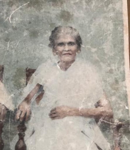 A photograph of Palayil Sreedevi wearing a white dress and sitting on a chair
