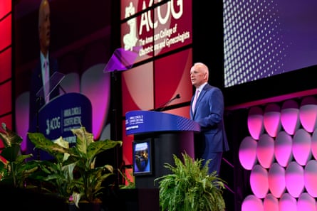 a man in a suit speaking at a podium