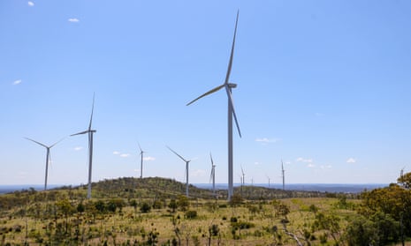 Wind turbines towering over a hilly landscape of grasses and stubby trees