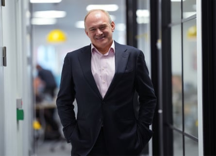 Lib Dems leader Ed Davey, dressed in pink shirt and dark suit, standing in a corridor