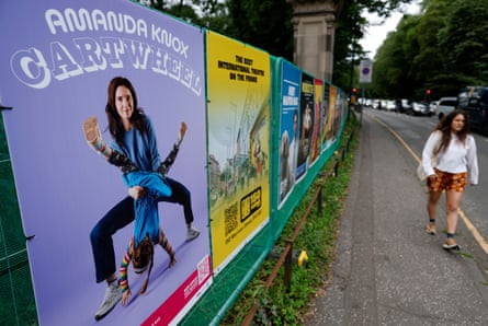 A woman walks past a poster for Cartwheel, which shows Knox holding a carthwheeling girl