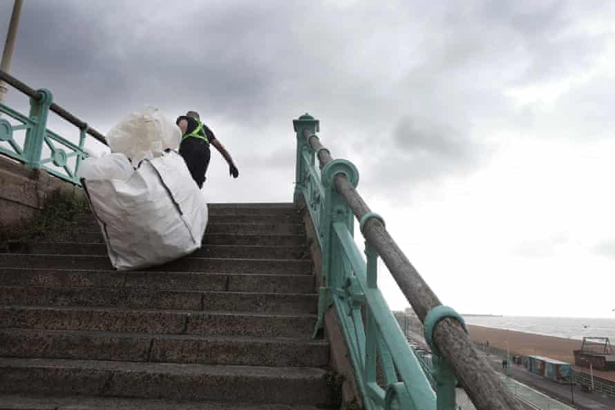 Rob dragging a large bag up stairs on Brighton seafront.