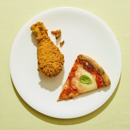 Homemade fried chicken and slice of pizza on white plate against green background