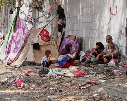 A displaced Yemeni family sits beside a makeshift shelter in Aden.