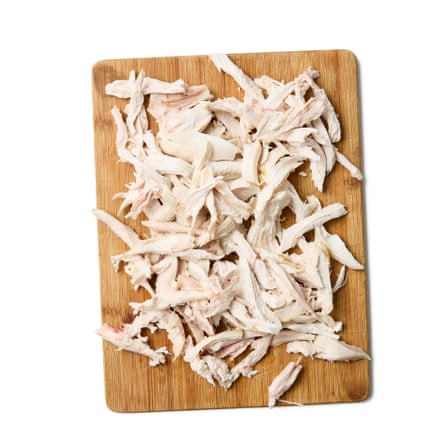 Shredded chicken on a chopping board: Strain the stock and strip the meat from the bones, again if using. Return the stock to the pan and continue with the recipe from this point.)