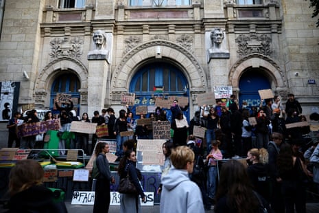Dozens of student protesters holding placards outside a school.