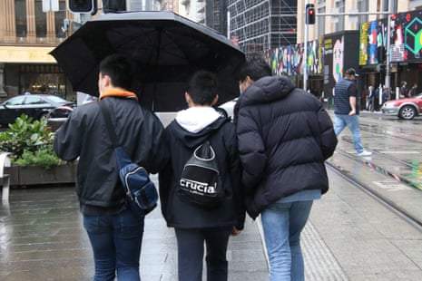 pedestrians under an umbrella in central Sydney