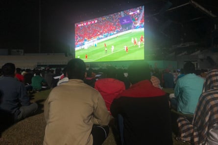 في منطقة المشجعين للعمال المهاجرين في الدوحة ، قطر ، يشاهد الناس مباراة إسبانيا ضد كوستاريكا ليلاً على شاشة كبيرة.