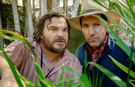 Two men surrounded by green leafs and looking sweaty, in the Amazon