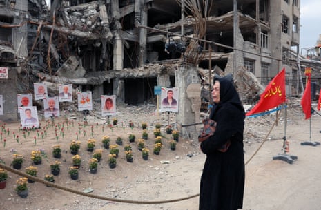 Женщина в черном и черном хиджабе плачет, глядя на фотографии, выставленные на мемориале возле здания, разрушенного в результате американо-израильского авиаудара. На фотографиях изображены все жертвы, погибшие в результате авиаудара.