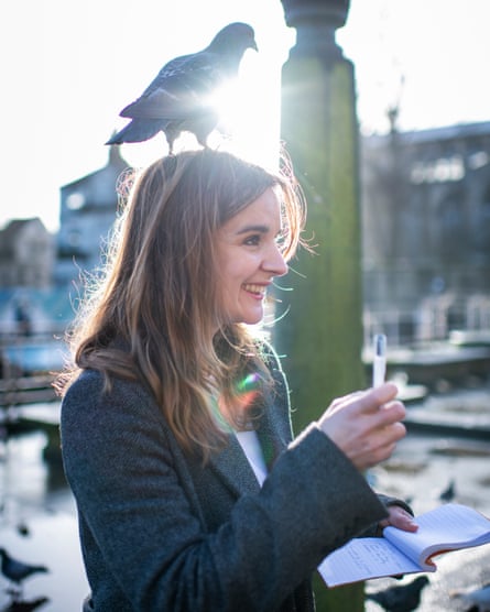 Guardian writer Elle Hunt with a pigeon on her head while reporting on the story at Norwich market.