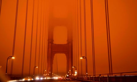 Cars drive along the Golden Gate Bridge under an orange smoke-filled sky – at midday in San Francisco.