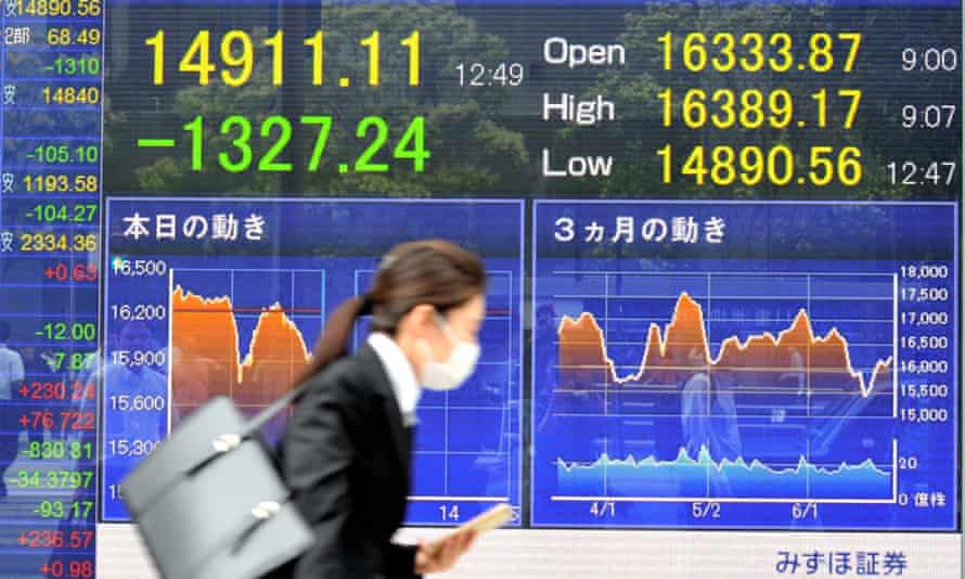 Young Japanese woman walking past stock market board