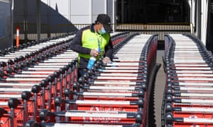 An airport worker cleans airport trolleys for passengers arriving at the International Airport Terminal in Sydney, Australia.