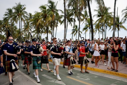 A parade of fans in Scotland shirts led by bagpipers