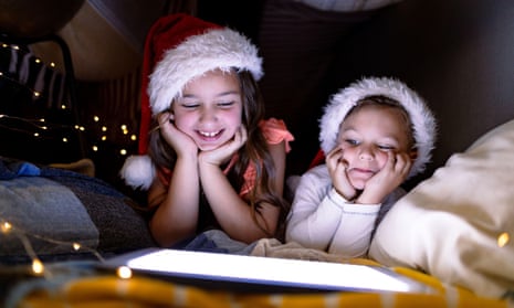Happy siblings wearing Santa hats and using a tablet at Christmas time