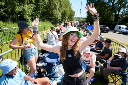 Carley Williams poses for the camera as people stand and sit behind her in a queue
