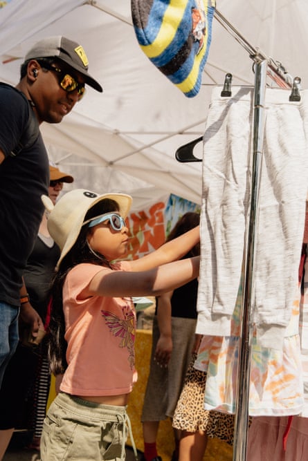a child looks at a clothing rack with an adult behind them