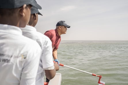 Biologist Nahi El Bar Jiyed scoops out a water sample at Banc d’Arguin national park as two students look on.