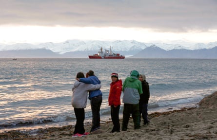 Local children stand on the shore as the Coast Guard ship Des Groseilliers sits in the waters near the Arctic community of Pond Inlet, Nunavut