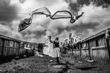 Elizabeth Nkere pegs washing on a line between wooden shelters