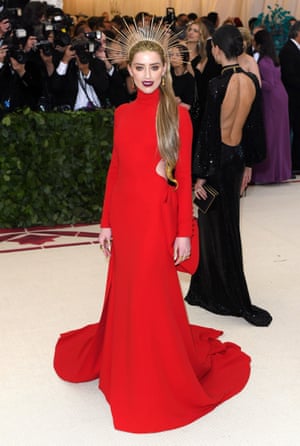 What better shortcut to the religious theme than a gold halo headpiece? Amber Heard matched her scarlet Carolina Herrera gown with the halo but her strong beauty look isn't winning many fans.