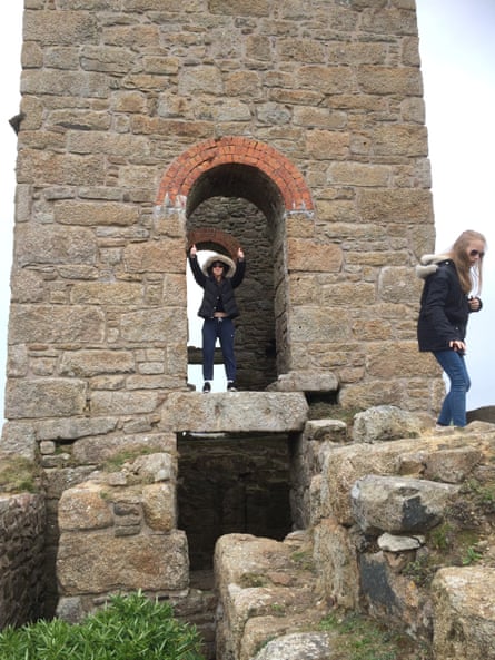 Two girls in jeans, coats and hoods explore what looks like an old castle tower