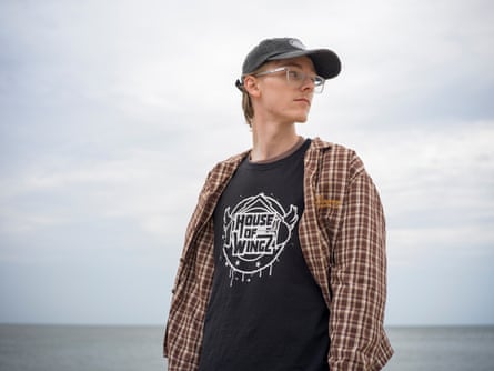 A young man in a cap with the sea behind him.