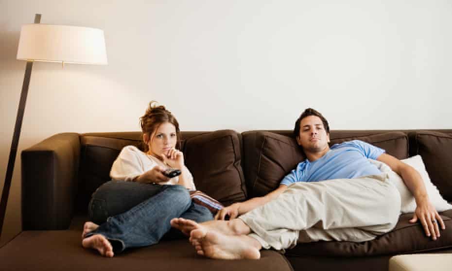 Young couple on sofa watching television. Posed by models