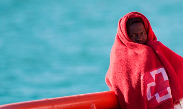 A migrant wrapped in a Red Cross blanket