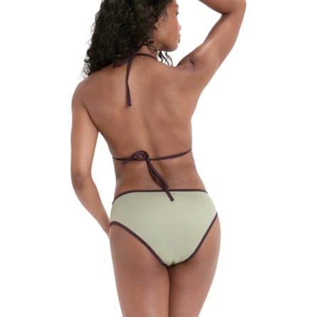 A woman stands with her back to the camera. She is wearing Snuggs Period swimwear olive coloured briefs