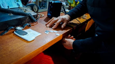 Sabanadze's hands sort through a small number of coins on the desk.