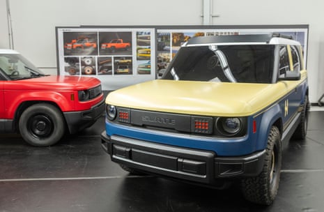 Two colorful electric vehicles displayed in a showroom with design boards in the background.