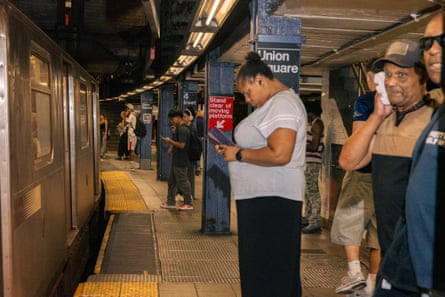 Commuters on a subway platform wait to board a train