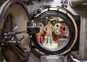 crew member photographed through a round door on a submarine