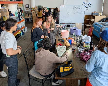 Fixit Clinic volunteers gather around a cluttered workbench examining tools and electronics