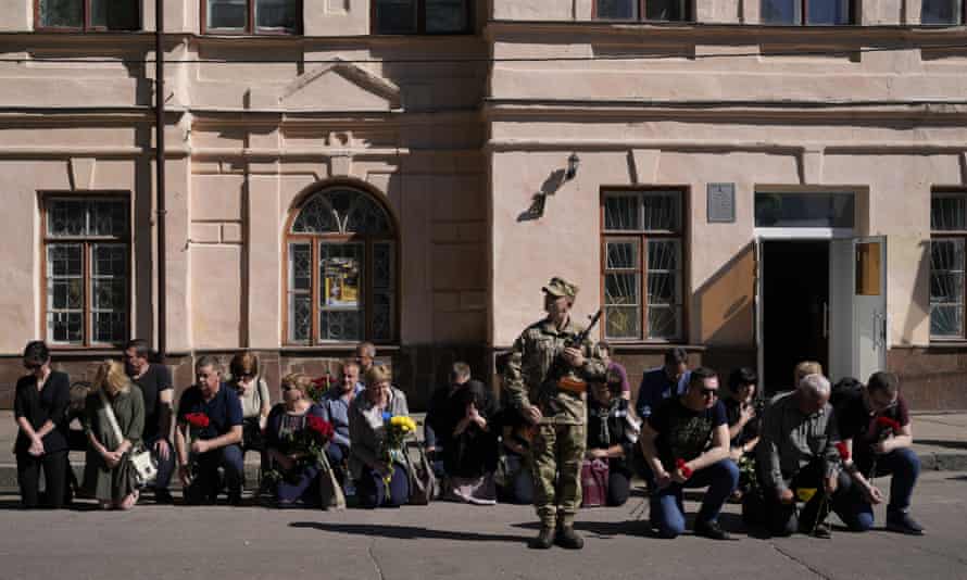 Friends and relatives of Army Col. Oleksander Makhachek kneel as a coffin with his remains arrives for a funeral service at a military base in Zhytomyr, Ukraine.
